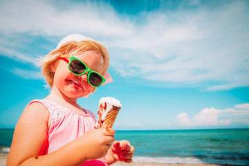 Poster - happy cute little girl eating ice cream on beach