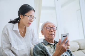 Wall Mural - Young woman teaching her father to use a phone