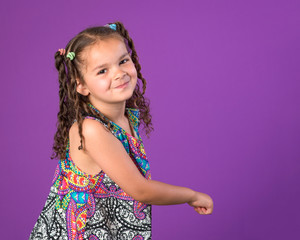 Smiling little girl dancing spinning playing isolated on purple background