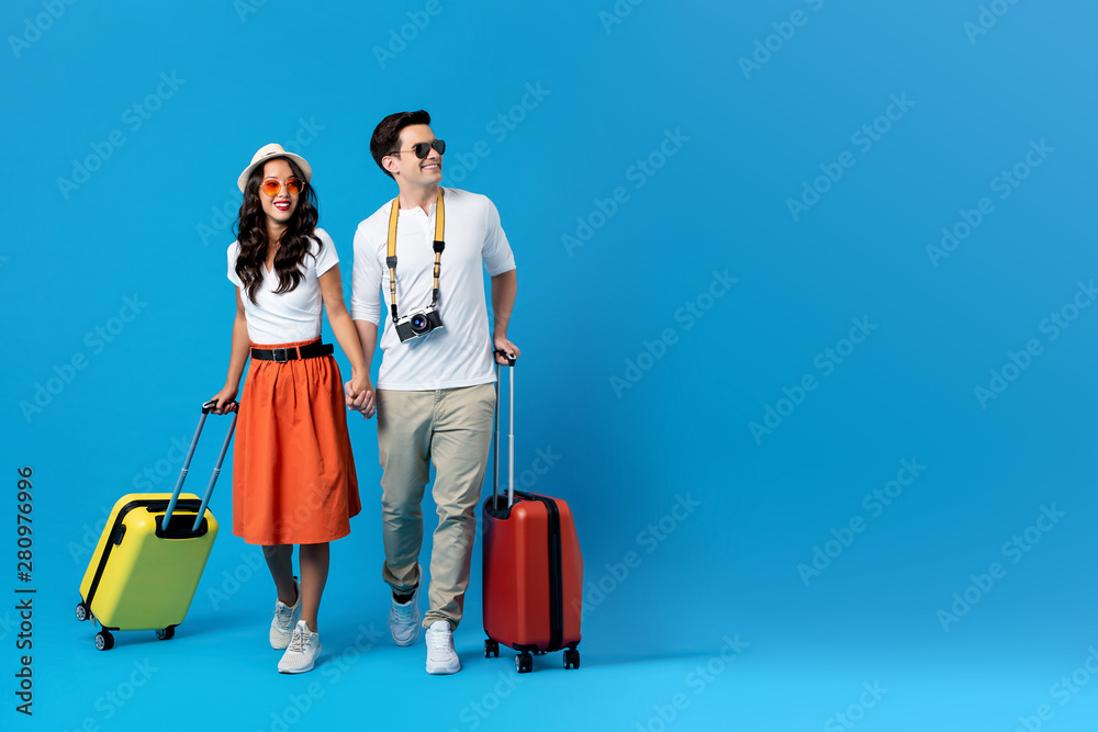 Young couple going for holidays with colorful suitcases - obrazy, fototapety, plakaty 