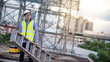 © zephyr_p - Asian maintenance worker man with safety helmet and green vest carrying aluminium step ladder and tool box at construction site. Civil engineering, Architecture builder and building service concepts