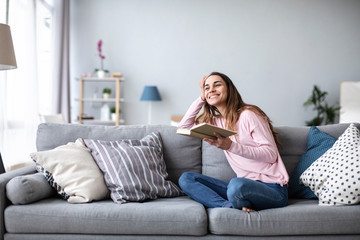 Wall Mural - Beautiful young woman reading book at home.