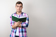 © Руслан Галиуллин - Young man student in plaid shirt reading book on grey background with copy space