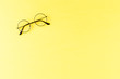 © One Pixel Studio - Black framed eyeglasses on yellow table. Top view