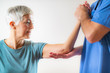 © Microgen - Therapist Checking Senior Woman’s Arm in Physical Therapy Office