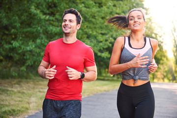 Wall Mural - Smiling young couple running in the park