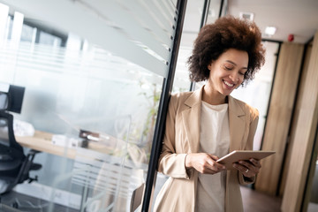 Portrait of an attractive young african businesswoman smiling while standing by windows in office