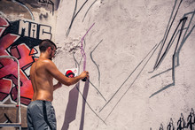 Graffiti Artist Painting A Wall In The Street