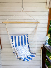 Blue And White Striped Pattern String And Cotton Hammock Hanging Chair, White Painted Wooden Board Background. Relaxing In Countryside Home Garden Balcony Outdoors On Summer Day Concept.