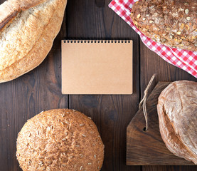 open notepad with empty brown sheets and baked bread rolls