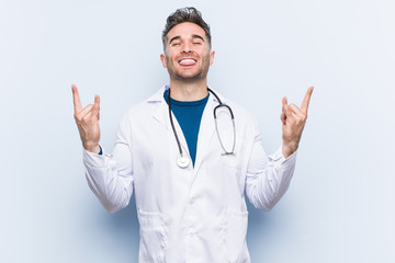 Young handsome doctor man showing rock gesture with fingers