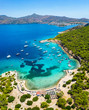 canvas print picture - Der beliebte Strand auf der kleinen Insel Moni gegenüber von Perdika bei Ägina mit türkisem Meer und zahlreichen Segelbooten, Griechenland