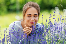 Gardening And People Concept - Happy Young Woman Smelling Lavender Flowers At Summer Garden