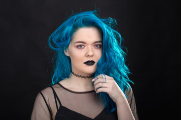 Wall Mural - People and fashion concept - Young and attractive woman with black lipstick and blue hair posing over black background