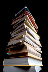 high pile of used books on a dark background