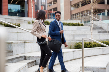 Businessman And Businesswoman Commuting To Work Walking Down Steps Outside Office Building