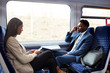 Business Passengers Sitting In Train Commuting To Work Using Mobile Phones