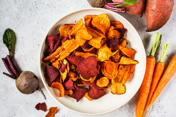 Bowl of healthy vegetable chips from beets, sweet potatoes and carrots on white background.