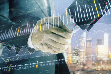 Double exposure of financial chart on cityscape background with two businessmen handshake. Concept of financial analysis and investment opportunities