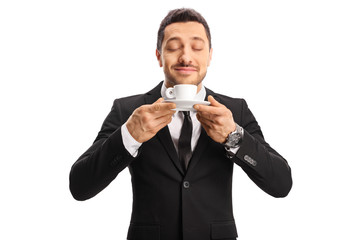 Young man in a suit enjoying the smell of a coffee