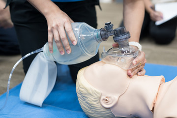 Wall Mural - Demonstrating CPR (Cardiopulmonary resuscitation) training medical procedure on CPR doll in the class.Paramedic demonstrate first aid practice for save life.Doctor holding breathing bag(Ambu bag).