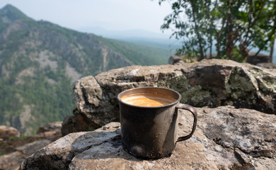 Coffee in a metal mug brewed on a fire in nature in the mountains. Coffee in nature