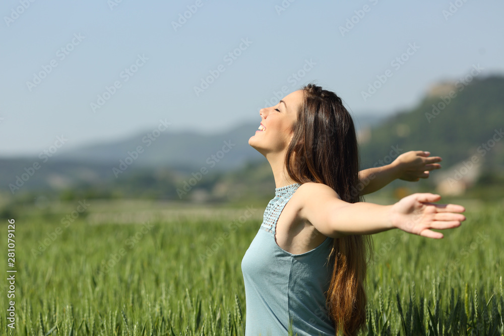 Happy woman breathing deeply fresh air in a field - obrazy, fototapety, plakaty 