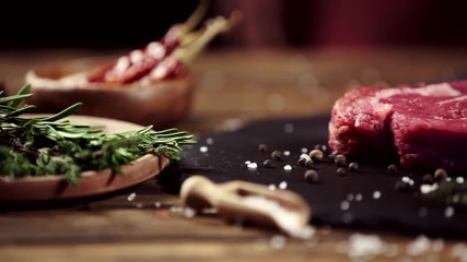 Wall Mural - falling rosemary on raw meat steak on table with ingredients