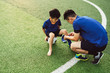 © MaaHoo Studio/Stocksy - Father putting socks on his son on soccer field