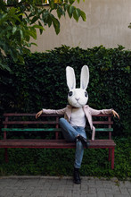 Woman In Rabbit Mask Sitting On Bench In Park