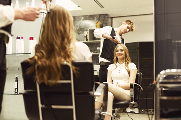 Wall Mural - Hairdresser Creating Curly Hairstyle To Smiling Girl In Salon