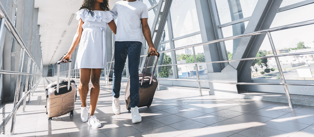 African couple walking with luggage in airport - obrazy, fototapety, plakaty 