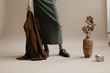 © Nicole Mason/Stocksy - modern portrait of model wearing long skirt holding a brown jacket in photo studio