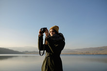 Young Woman Taking Picture With Digital Camera By Lake