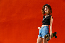 Young Girl Portrait With Skateboard On Red Orange Wall