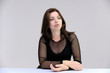 © Вячеслав Чичаев - Portrait of a pretty beautiful fashionable adult girl with beautiful brunette hair in a black dress. Sits at the table directly in front of camera, talking demonstrating different poses and emotions