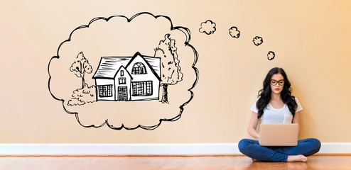 Wall Mural - Dreaming of new home with young woman using a laptop computer