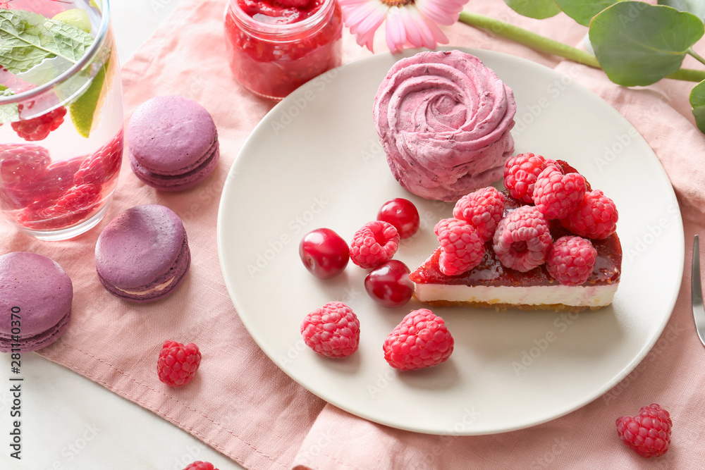 Plate with tasty raspberry desserts and lemonade in glass on table