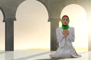 Wall Mural - Asian Muslim woman sitting in pray position while raised hands and praying