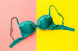 Green female bra on yellow and pink background. Flat lay.