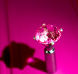 Diamond shaped pink gem locked into a metal stand