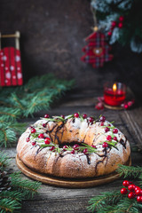 Traditional homemade christmas cake holiday dessert with cranberry and chocolate with new year tree decoration on vintage wooden table background. Rustic style.