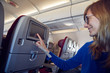 © astrosystem - Woman using touchscreen in modern airplane seat.