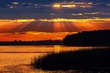 Fototapeta Las - Romantyczny zachód słońca nad jeziorem z promieniami słońca w chmurach