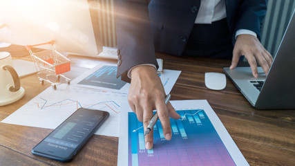Poster - Businessman analyzing sales data and economic growth and    pointing at business report document with graph chart financial diagram, marketing, banking and payments, business planning and strategy.