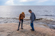 © Tatyana_Andreyeva - Middle aged man and young lady walking on northern lake shore in summer day. Tourists exploring ancient petroglyphs. Travelling and discovering distant places of Earth. Onega lake, Karelia, Russia