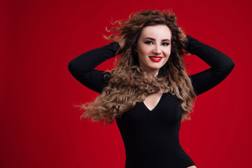 Young woman with her hands behind her head, red lips and curly hair posing. Beautiful woman with clean fresh skin and healthy curly hair. Sexy young woman with perfect make up. Afro curls hair.