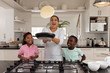 Mother and children preparing food on a worktop in kitchen
