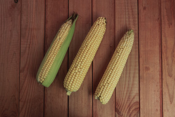 Poster - Fresh Sweet corn  on a red wooden table background.