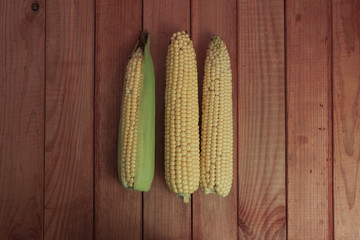 Poster - Fresh Sweet corn  on a red wooden table background.